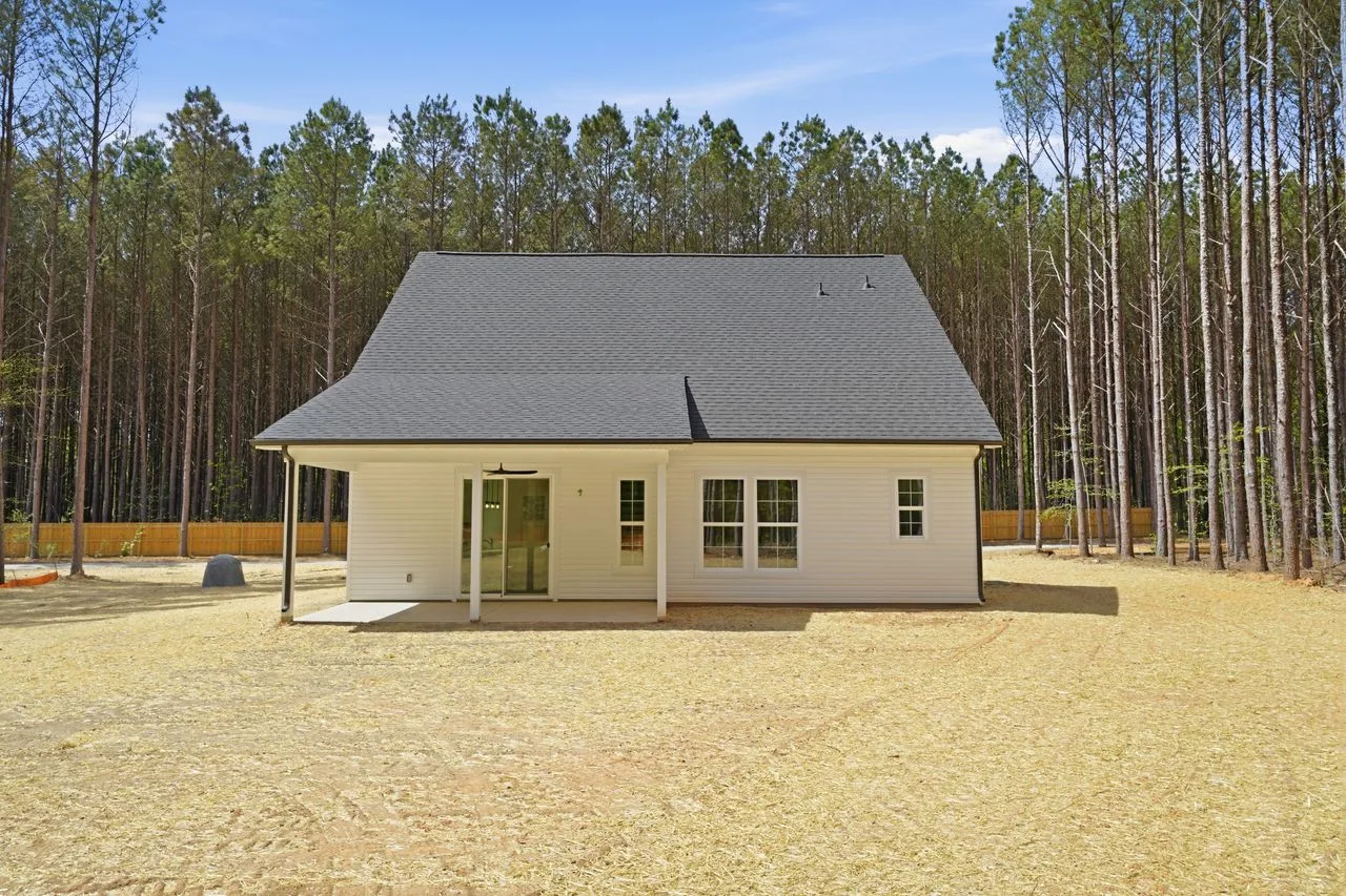 Rear exterior of 1424 Quiver Way showing covered porch and tree line — York SC