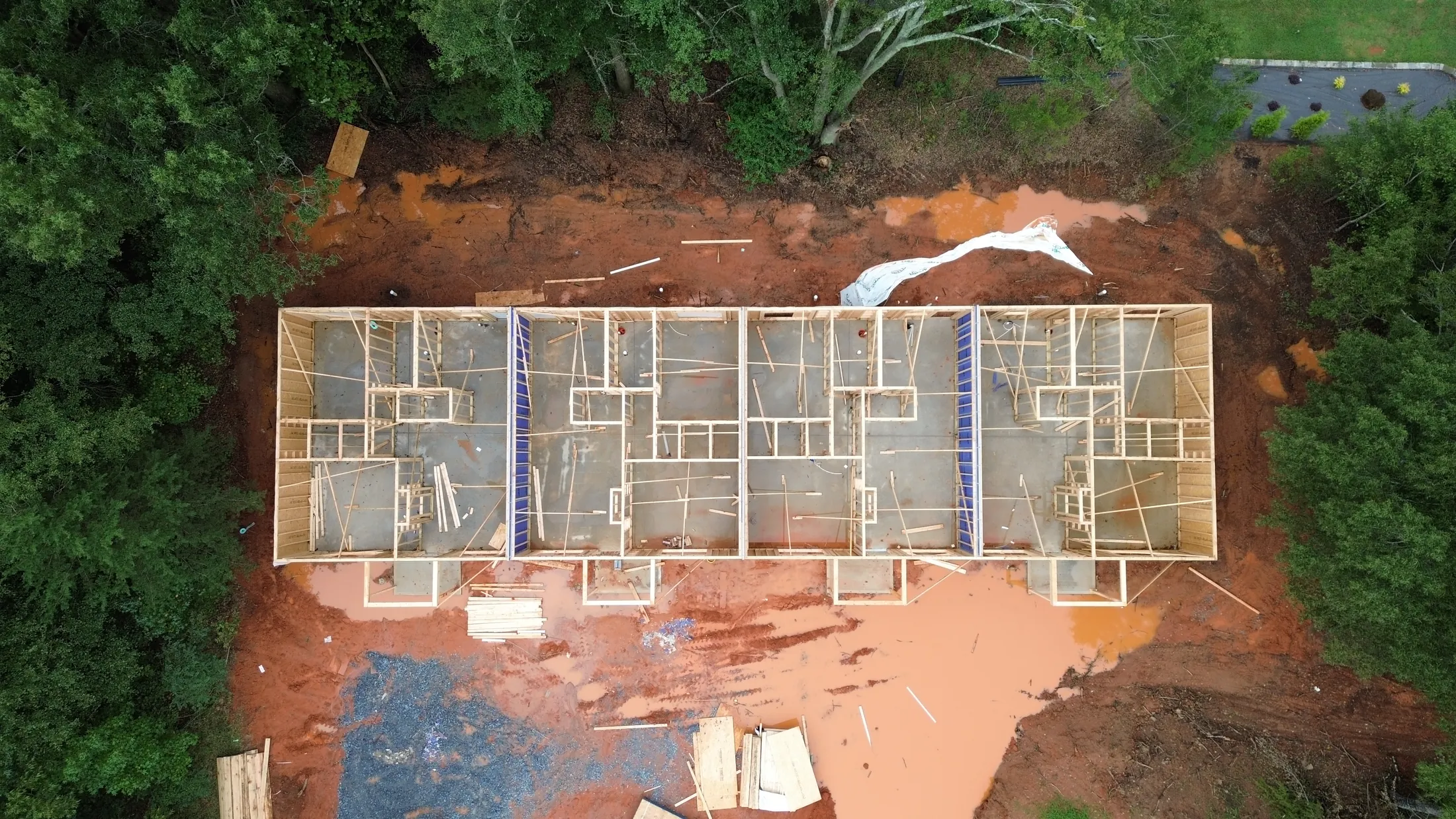 Top-down drone view of the build-to-hold Clover quadplex showing four framed units on the concrete slab